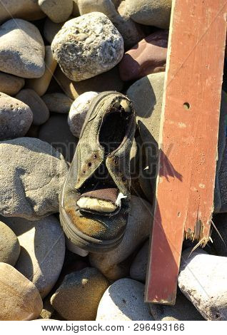 Beach Rubbish Brown Wood Plank And Old Shoe On Pebble Rocky Beach