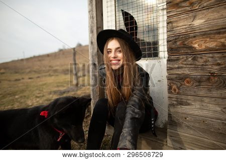 Happy Young Woman Plaing With Her Black Dog Brovko Vivchar In Fron Of Old Wooden House