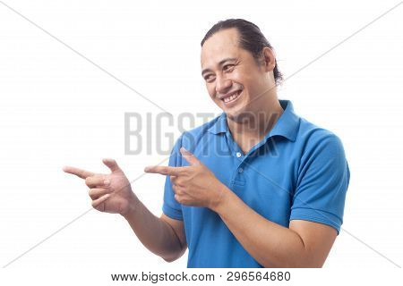 Young Asian Man Wearing Blue Shirt Smiling, Showing And Pointing Something On His Side, Isolated On 