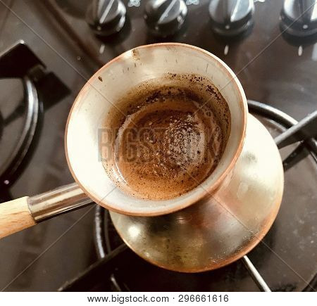 Barista Preparing Hot Tasty Drink From Copper Turk, Boils Water For Coffee On Small Fire In Cezve. C
