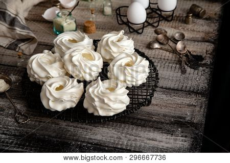 Homemade White Mini Meringue Desserts Pavlova On Wicker Metal Stand On Grey Wooden Table With Bottle