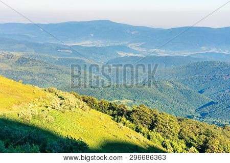 Beautiful Mountain Landscape At Summer Forenoon. Hills With Grassy Meadows Among The Forest. Dirt Ro