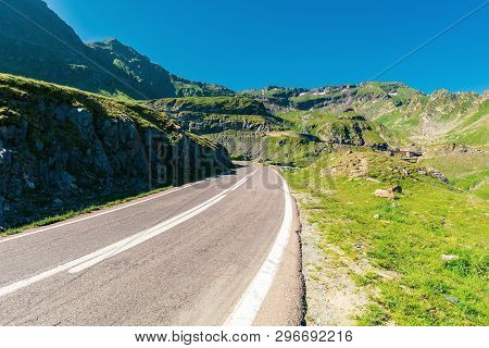 Transfagarasan Road Though Mountains. Wonderful Sunny Forenoon Weather. Rocky Slopes And Grassy Hill