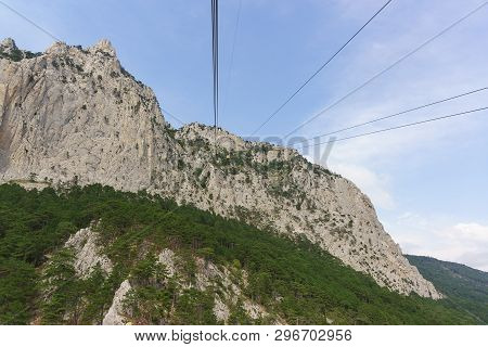 Yellow Cableway Tourist Cable Car Rises To The Top Of The High Crimean Mountain Ai-petri. Rocks Over