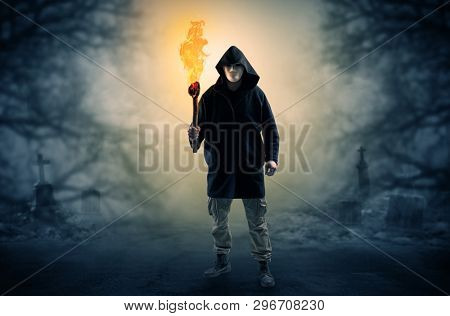 Man with burning flambeau coming from thicket and looking something