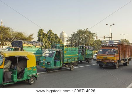 Delhi India - 09.02.2019 Indian Green Moto Trucks In City Traffic On A Background Of Green Trees And