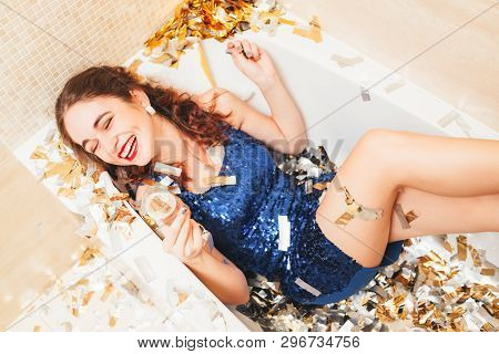 Luxe Fashion Style Festive Event. Spoilt Brunette Girl In Blue Dress Lying In Bathtub With Legs Up, 