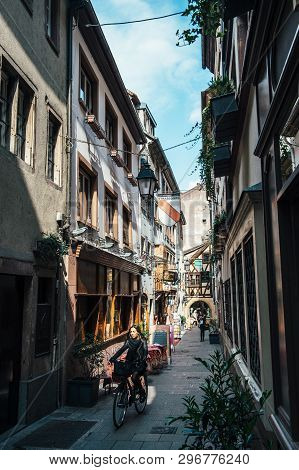 Strasbourg, France - Apr 19, 2016: Adult Woman On Bike On Cute Street Tiny Vintage Timbered Houses B