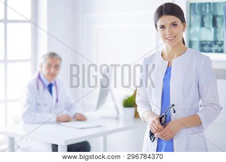 A doctor looking at the camera with her male colleage in the back of the conference room in hospital