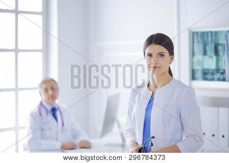 A doctor looking at the camera with her male colleage in the back of the conference room in hospital