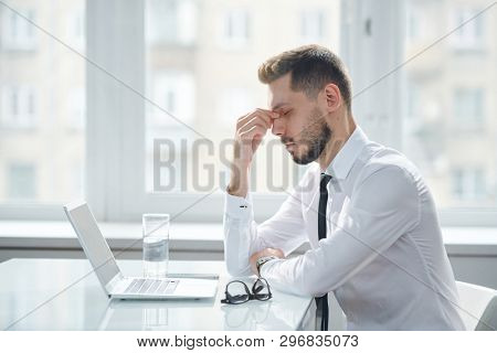Young tired and tense manager trying to concentrate while working over project and thinking of ideas