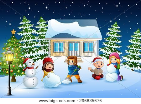 Happy Kids Wearing A Winter Clotes Making A Snowman In Christmas Day