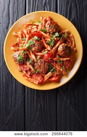 Meatballs With A Side Dish Of Pasta Casarecce In Tomato Sauce Close-up On A Plate. Vertical Top View