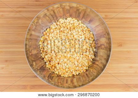 Raw Yellow Variety Of The Split Peas In Stainless Steel Bowl On A Bamboo Wooden Surface, Top View