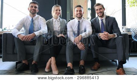 Group Of Four Business People Sitting On Sofa. Were The Team You Need If You Want To Succeed.