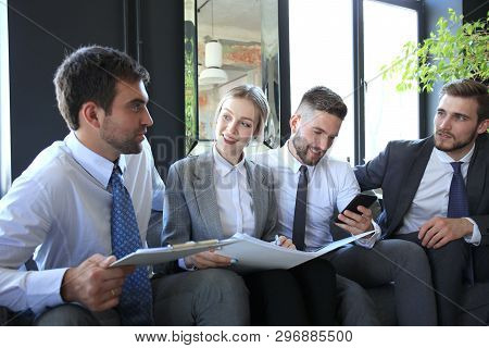 Group Of Four Business People Sitting On Sofa. They Couldnt Be Happier About Working Together.