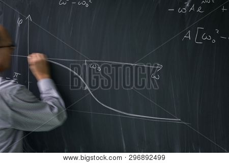 Math teacher drawing   fuction graph on a blackboard during mathclass (motion blurred image)