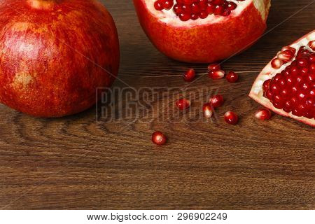 Stil Life - Red Whole And Cutted Pomegranate Fruits, Scattered Seeds And Glass With Juice On A Dark 