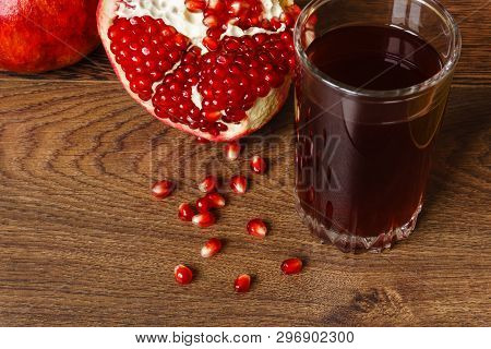 Stil Life - Red Whole And Cutted Pomegranate Fruits, Scattered Seeds And Glass With Juice On A Dark 