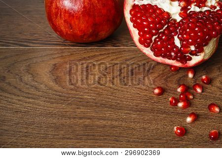 Stil Life - Red Whole And Cutted Pomegranate Fruits And Scattered Seeds On A Dark Wooden Tabletop