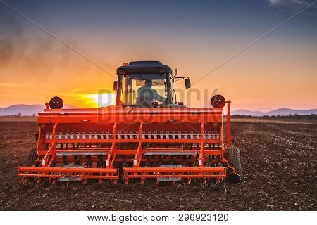 Beautiful Sunset, Farmer In Tractor Preparing Land With Seedbed Cultivator