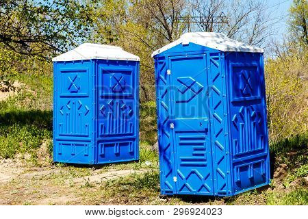 Two  Blue  Cabines Of Chemical Toilets In A Park At Sunny Summer Day.