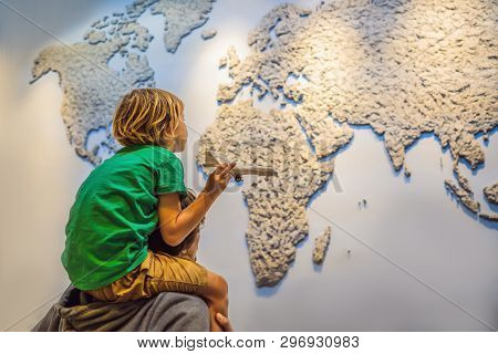 Dad And Son On The Background Of A World Map With An Airplane In His Hands. Travel Concept