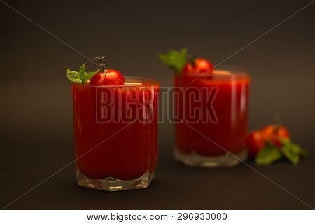 Two Glasses Of Tomato Juice With Cherry Tomatoes And Mint With A Black Background