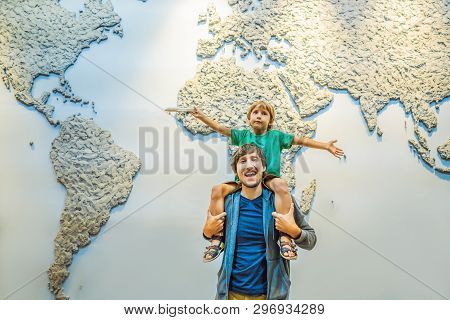 Dad And Son On The Background Of A World Map With An Airplane In His Hands. Travel Concept