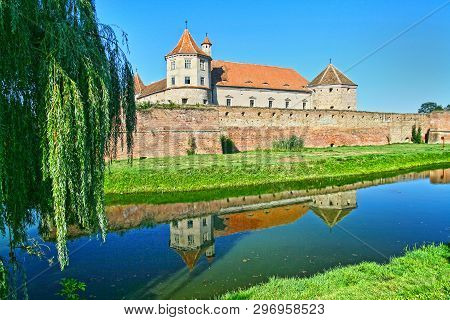 Summer Scene At Fagaras Fortress Mirroring. Built In 1310, The Fortress Is Surrounded By A Deep Moat