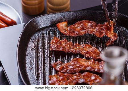 Young Woman In A Gray Apron Fries Bacon