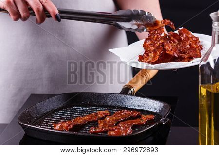 Young Woman In A Gray Apron Fries Bacon