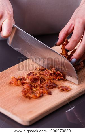 Young Woman In A Gray Apron Cuts Roasted Bacon