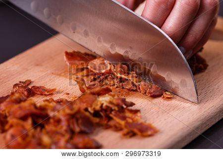 Young Woman In A Gray Apron Cuts Roasted Bacon