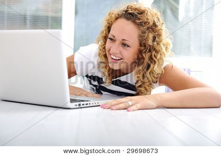 Meisje thuis met laptop liyng op grond