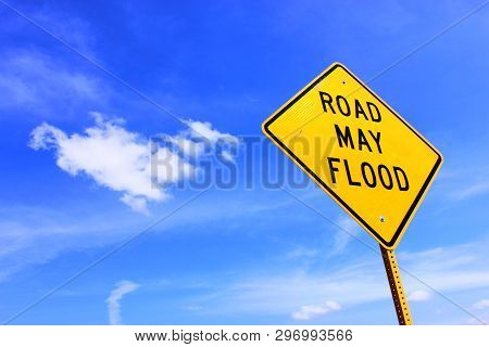 Road Side Sign Warning That The Road May Flood Set Against A Blue Sky With Clouds