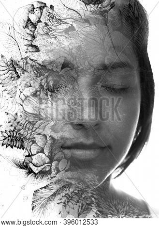 A black and white portrait of a young beautiful brunette with her eyes closed, half smiling combined with a floral drawing in a paintogrphy technique against white background