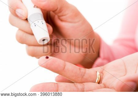 Closeup Woman Measuring Glucose Level Using A Hand Test Lancelet On The Finger She Monitors High Blo