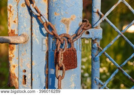 Old rusty gate locked by a padlock and chain