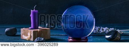 Fortune Telling Panorama. A Magic Ball With A Candle, Crystals And Herbs, A Side View On A Dark Back