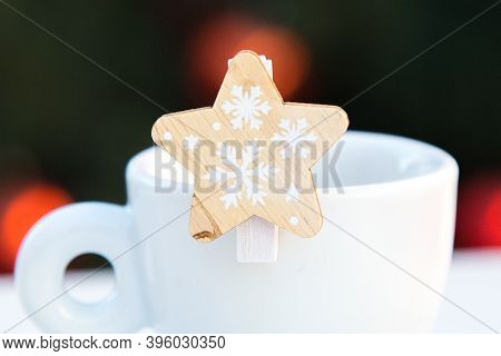 Wooden Decorative Star With Snowflakes Closeup On White Porcelain Coffee Cup. Blurred Background Wit