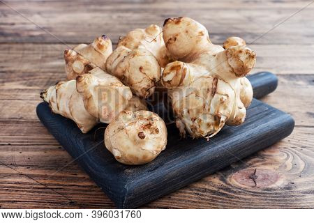 Raw Jerusalem Artichoke, Topinambur Tubers On A Rustic Wooden Background. Copy Space.