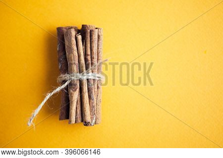 Cinnamon Sticks Held Together With Jute Rope On The Yellow Background With Copy Space For Your Text