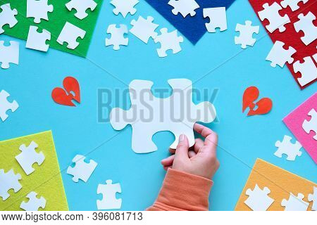 Autism Awareness Concept. Flat Lay, Hand, Jigsaw Puzzle Pieces. Text Space On Blue Background.