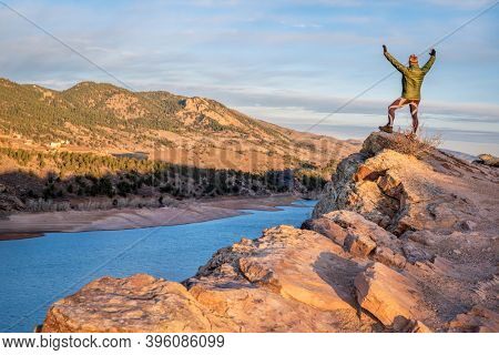 happy male hiker on a cliff overlooking Horsetooth Reservoir, popular recreation destination for boating, hiking and biking in northern Colorado, fall scenery at sunrise
