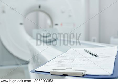 Clipboard with medical document and pen lying on couchette that is part of contemporary medical equipment inside clinics or hospital