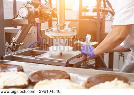 The Pastry Chef Makes Cake Using Modern Equipment For The Production Of Cakes. Line For Spreading Cr
