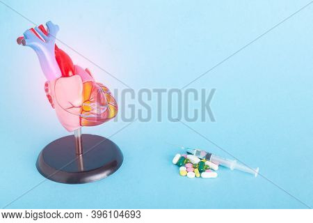 Mock Up Human Heart, Pills And Syringe On A Blue Background. Concept Of Heart Disease Treatment With