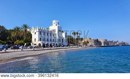 Kos, Greece - September 17, 2019: Kos Town Police Station And Castle Overlook A Pebble Beach On Kos 