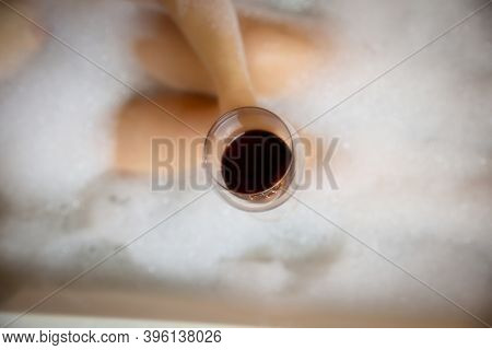 Young Woman's Hand Holding Wine Glass In Bathtub, Drinking Red Wine And Lying In Bathtub With Bubble